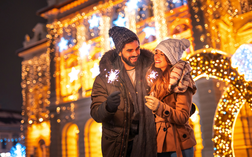 Paar feiert Neujahr im Freien, hält Wunderkerzen in der Hand und umarmt sich. - © Impact Photography - stock.adobe.com